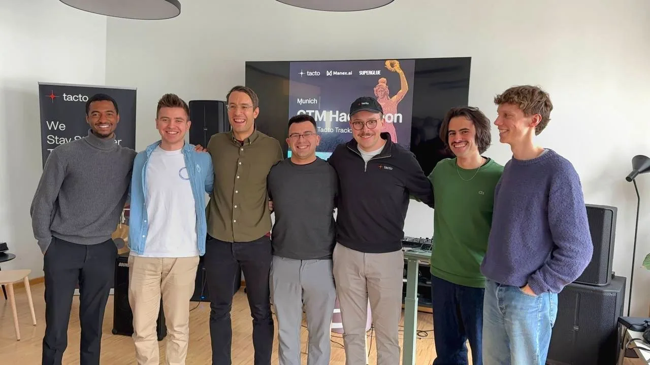 Das Gewinnerteam der Tacto-Challenge beim GTM Hackathon München vor der Leinwand mit dem Veranstaltungsplakat