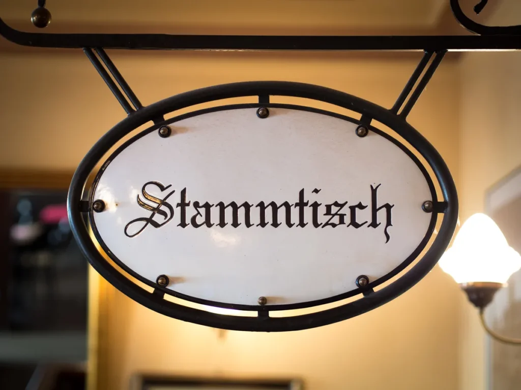 Emailliertes Schild mit der Aufschrift Stammtisch über einem Tisch in einem Münchner Wirtshaus